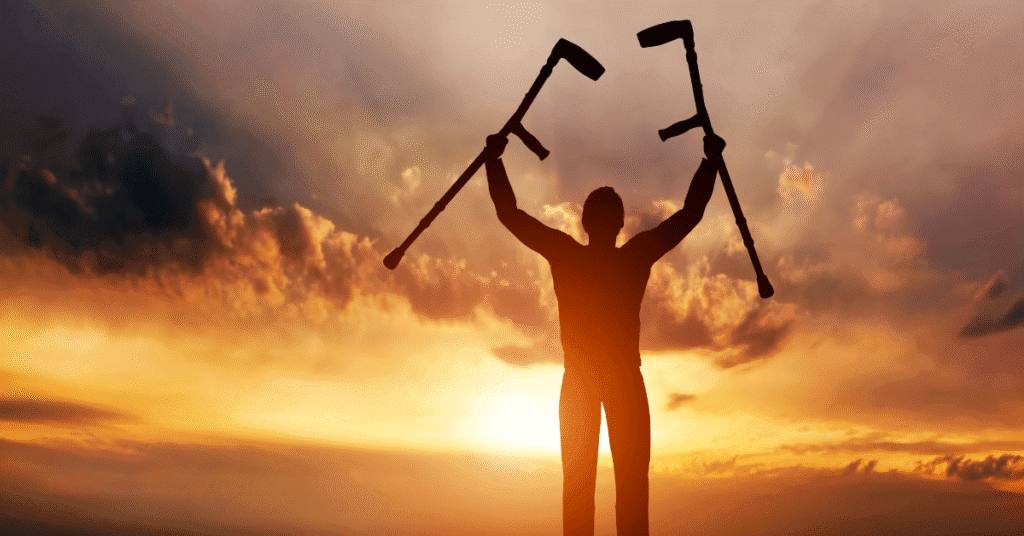 Persona levantando muletas al amanecer, símbolo de recuperación y retorno laboral.