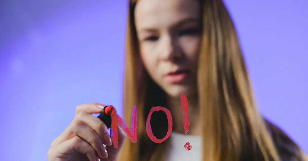 Mujer joven escribe la palabra “NO” en un vidrio, simbolizando la eliminación del concepto “No Apto” en exámenes ocupacionales según la Resolución 1843 de 2025.