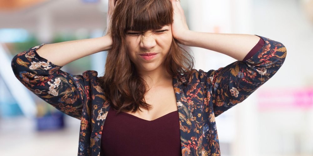 young woman covering her ears young woman covering her ears